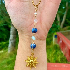 Golden sun pendant necklace with pearl and blue crystal beads on a beaded chain