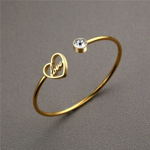Detailed macro view of gold heart bracelet featuring love engraving and sparkling zircon stone