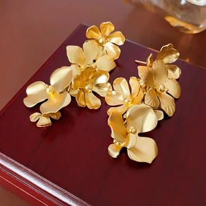 Macro de boucles d'oreilles fleurs dorées sur boîte en bois vintage aux pétales 3D