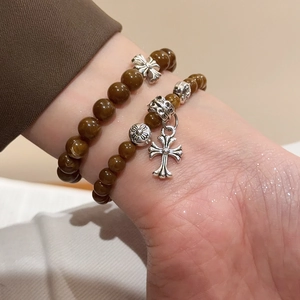 Détail de bracelets à perles double épaisseur avec breloques croix argentées au poignet