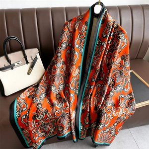 Détail d'un châle en satin de soie avec imprimé paisley orange et texture brillante