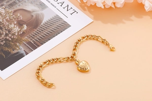 Close-up of golden heart pendant on chunky stainless steel chain over warm orange background