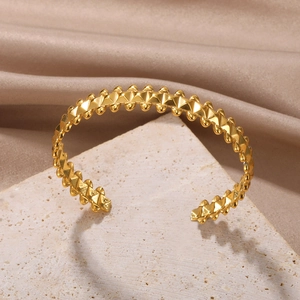 Detail of golden geometric bangle with pyramid studs and fine bead texture on stone base