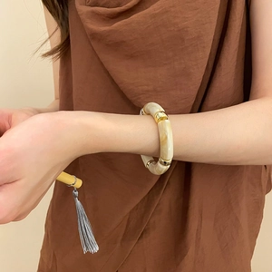 Detail view of chunky acrylic marble bangle with gold metal beads on wrist