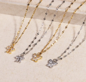 Détail de pendentifs papillon dorés et argentés avec zircons sur chaînes en métal élégantes