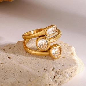 Gold multi-layer heart and square zircon ring on light stone background