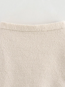 Detailed close-up of beige bouclé knit fabric texture and ribbed round neckline design