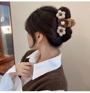 Detail of three handmade knitted flowers on a hair claw clip with wool texture