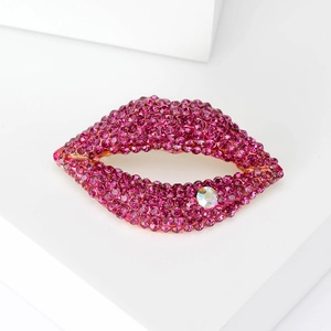 Macro detail of lip-shaped brooch with pink rhinestones and clear crystal on gold base