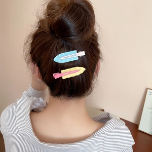 Detail of pink, blue and yellow wave-shaped matte hair clips worn on brown hair