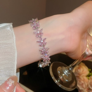 Close-up of pink zircon flower bracelet on wrist with elegant silk sleeve background