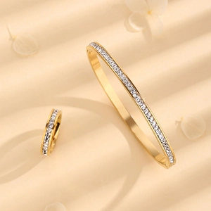 Luxury gold stainless steel bracelet and ring set with square zircon inlay on beige table