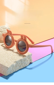 Detail of orange round kids sunglasses with cute rabbit ears on a colorful background