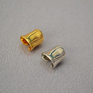 Detail von minimalistischen breiten Wellen-Ohrklemmen in poliertem Gold und Silber