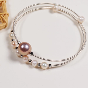 Macro detail of a double-layer silver wire bracelet with freshwater pearls on white