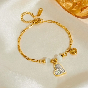 Détail du bracelet pendentif cœur doré avec perles opale sur fond en soie premium
