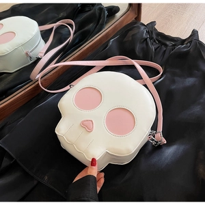 Detail showing skull-shaped crossbody bag with pink heart eyes and silver zipper hardware