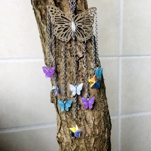 Detail of silver butterfly suncatcher with colorful prisms hanging on a branch