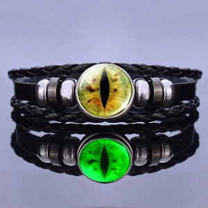 Detailed view of leather bracelet with glowing green dragon eye glass bead on mirror