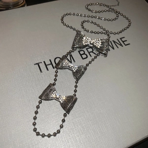 Close-up of silver beaded necklace featuring three shimmering rhinestone bow pendants