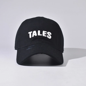 Close-up of TALES embroidery and distressed brim details on a black cotton baseball cap