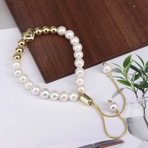 Close-up of elegant pearl bracelet with gold heart charm and adjustable pull chain
