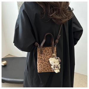 Detailed back view of a mini leopard print crossbody bag with a cute cat charm accessory