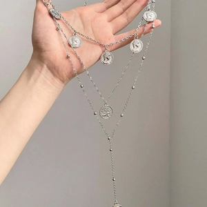 Close-up of triple-layered silver necklace with vintage portrait coin pendants and metal beads