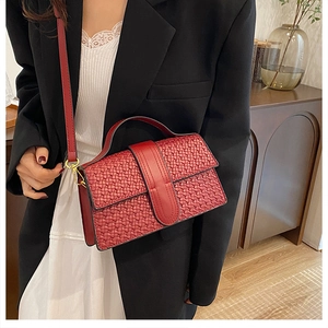 Detail shot of a dark red woven texture crossbody bag with elegant gold metal hardware