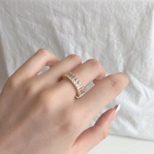 Close-up of gold ring with rectangle cut clear stones worn on a finger