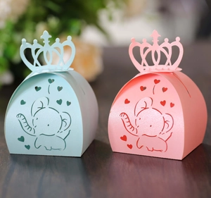 Detail of pink and blue laser-cut candy boxes with crown handles and elephant motifs