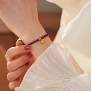 Detail of red cinnabar beads with a golden pumpkin pendant on a vintage style bracelet