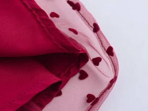 Détail de la robe rouge à manches bouffantes en tulle avec motifs de cœurs floqués et coutures