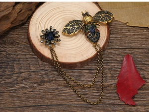 Detailed view of vintage bee chain brooch with blue gemstones and crystals on wood
