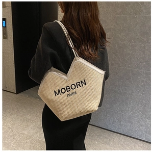 Close-up of woven straw tote bag with MOBORN PARIS black embroidery and slender shoulder strap