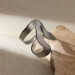 Macro detail of silver snake-shaped irregular curve ring on a natural stone base