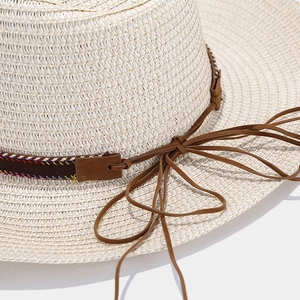 Detailed view of woven straw hat featuring a decorative band with embroidery and suede bow