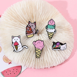 Close-up of five cute cartoon cat ice cream enamel pins on a pink decorative background