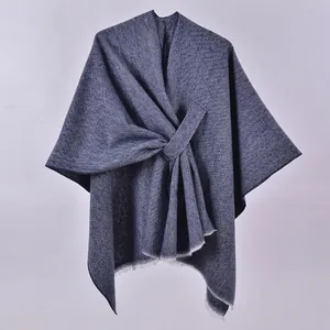 Detail of navy blue knitted poncho featuring twill weave texture and delicate fringe edges