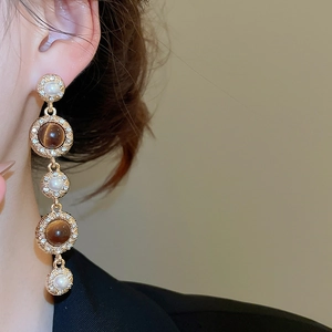 Detail of vintage palace style dangling earring with tiger eye stone and pearls on model