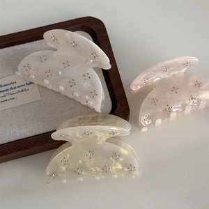 Close-up of three acetate hair claws in cream and pink with sparkling rhinestones