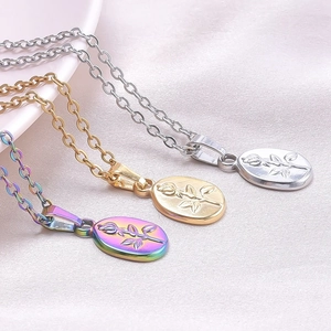 Macro shot of oval rose embossed pendants in gold, silver and rainbow on pink silk