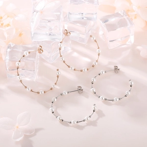 Close-up of gold and silver C-shaped pearl earrings on a decorative petal backdrop