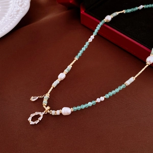 Macro view of aquamarine beads and Baroque pearls with a sparkling rhinestone pendant