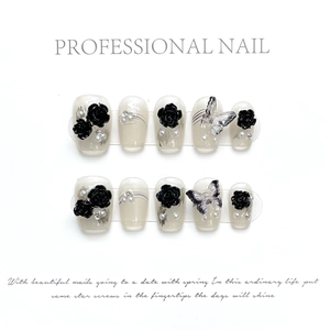 Detail of 10-piece press-on nails set featuring black 3D roses, butterflies, and pearls