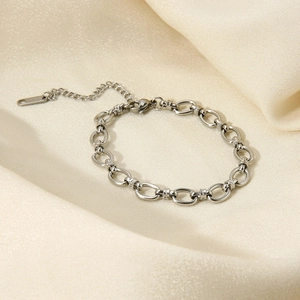 Close-up of silver oval link chain bracelet with lobster clasp on beige satin fabric