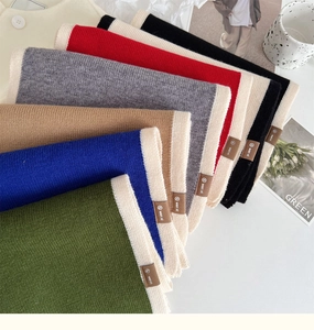 Detailed view of color-block knit scarves with contrast piping and leather logo patch