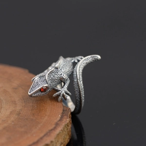 Macro shot of a vintage silver lizard ring featuring red stone eyes and scale textures