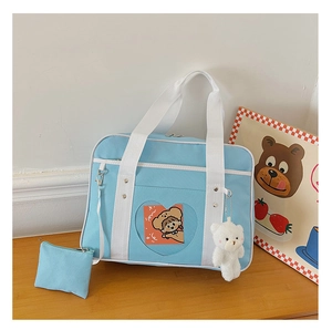 Detail of light blue JK uniform bag with heart-shaped window and plush bear charm