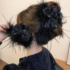 Close-up of a model wearing black feather and sequin bow hair clips with elegant details